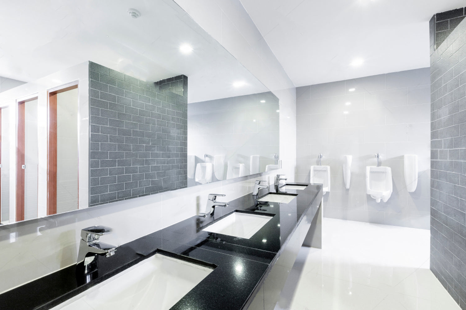 Modern bathroom with black countertop, white sinks, and gray tiled walls.